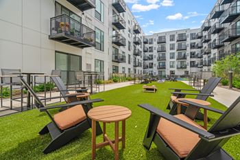 an open courtyard with chairs and tables in front of an apartment building